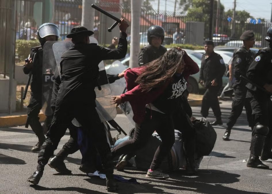 Policías antidisturbios golpean a una mujer en una calle