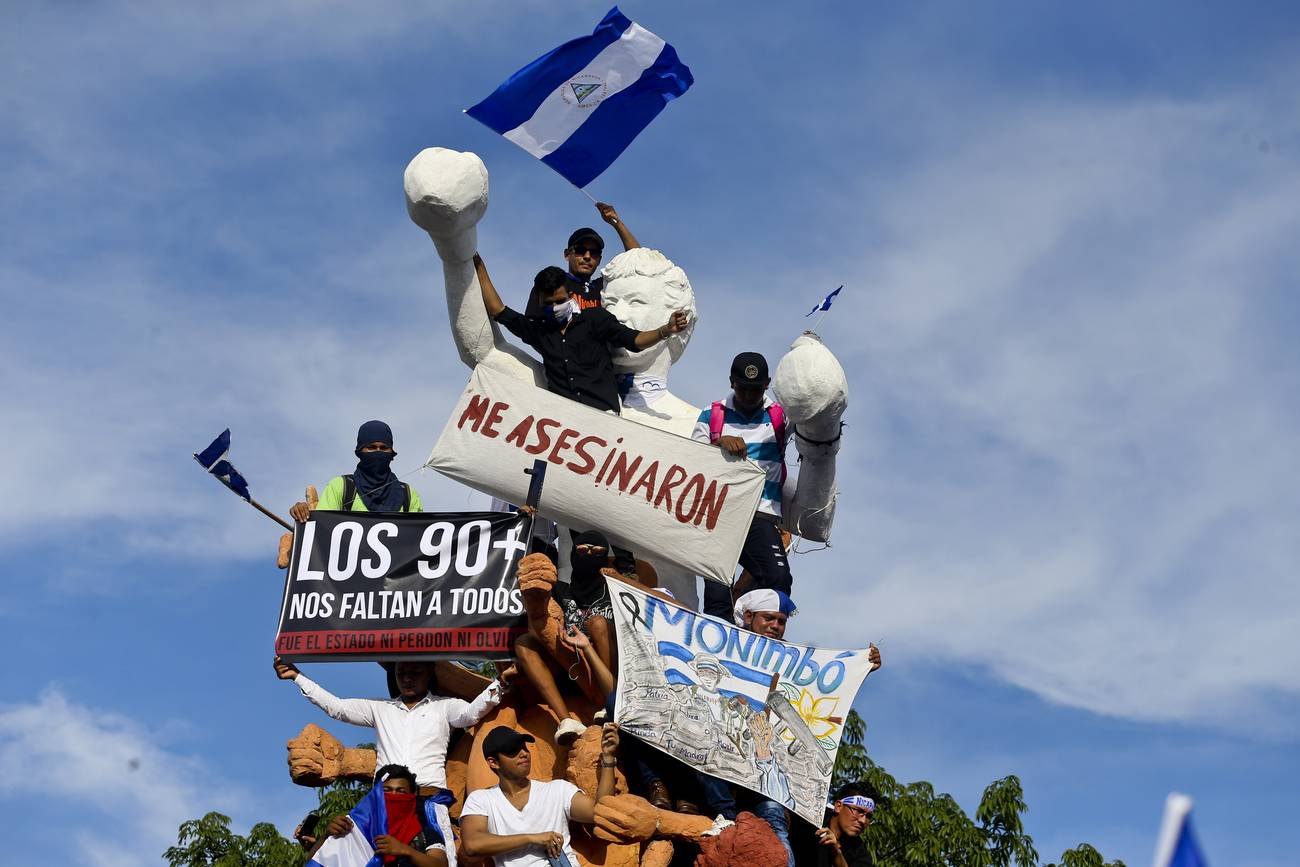 Monumento improvisado con letreros «Me asesinaron» y «Los 90+ nos faltan a todos», con banderas