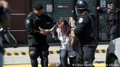 Policías detienen a un hombre frente a un comercio con la cortina bajada