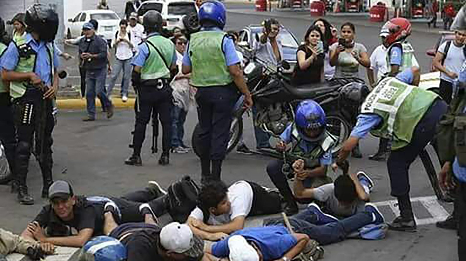 Policías y paramilitares junto a varias personas tendidas en el suelo