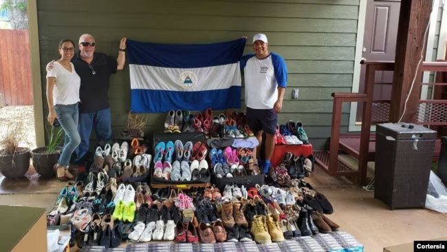 Una pareja posa con una bandera de Nicaragua frente a decenas de pares de zapatos