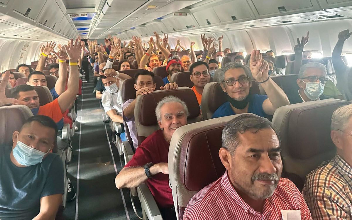 Pasajeros dentro de un avión levantan los brazos y hacen la señal de victoria