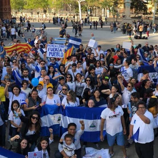 Multitud de nicaragüenses en una plaza con banderas azul y blanco